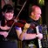 Una mujer toca el violín junto a un hombre que toca el acordeón cerca de un micrófono